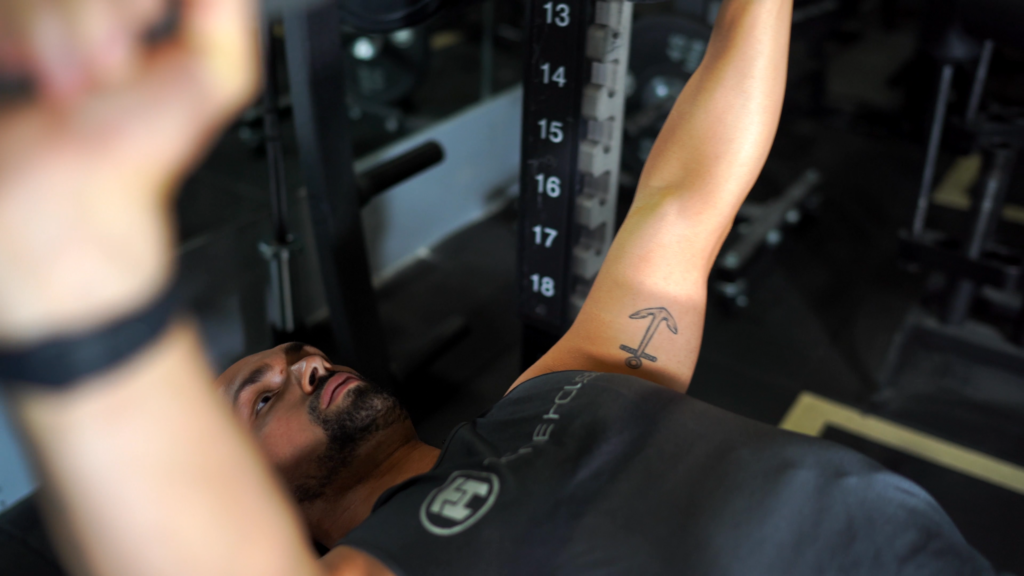 Coach Zack performing bench press; raised position; close up