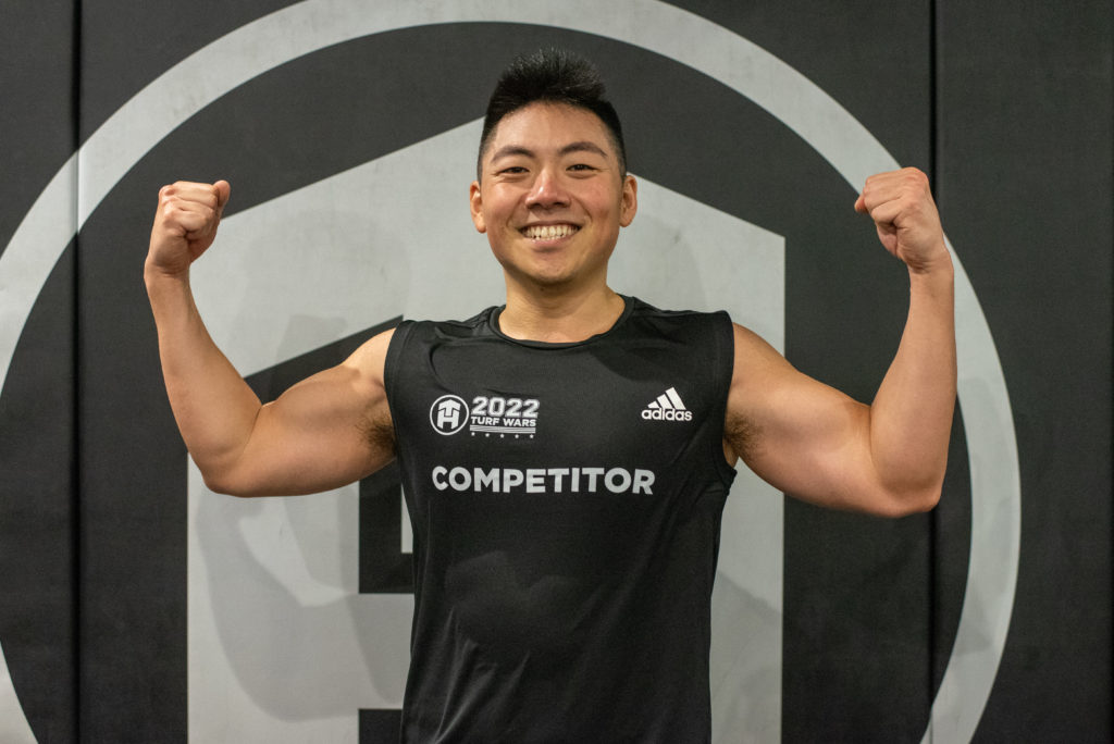 Muscle Build Challenge winner, Arthur Lee, flexing his arms in front of Tone House logo