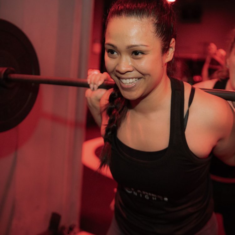 female athlete smiling at top of squat